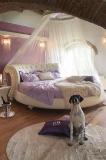 Στρογγυλό λευκό δερμάτινο κρεβάτι με ουρανό στο υπνοδωμάτιο