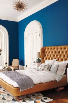 Καφέ δερμάτινο κρεβάτι σε ένα λευκό και μπλε υπνοδωμάτιο