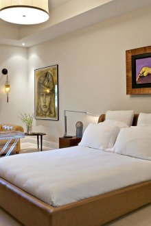 Καφέ δερμάτινο κρεβάτι σε μπεζ και λευκή κρεβατοκάμαρα