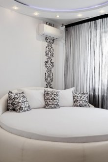 Στρογγυλό λευκό δερμάτινο κρεβάτι στο υπνοδωμάτιο