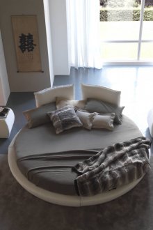 Γκρι και λευκό στρογγυλό κρεβάτι στο υπνοδωμάτιο με τζάκι