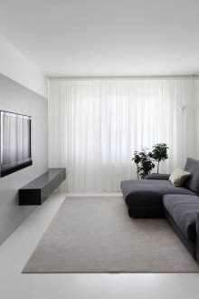 Μαύρος καναπές σε ένα λευκό καθιστικό με το στυλ του μινιμαλισμού