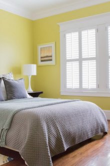 Γκρι κρεβάτι και λευκή και κίτρινη πολυθρόνα στην κρεβατοκάμαρα