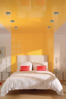 Προβολείς και επιτραπέζιοι φωτισμοί σε ένα λευκό και κίτρινο υπνοδωμάτιο