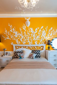 Πολυέλαιος, φωτιστικό δαπέδου και επιτραπέζιο φωτιστικό σε μια λευκή και κίτρινη κρεβατοκάμαρα