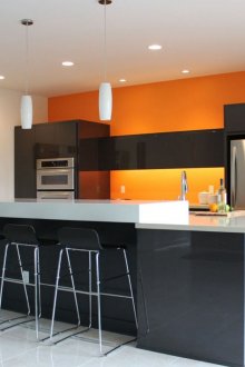 Πορτοκαλί τοίχο σε μια μαύρη και άσπρη κουζίνα