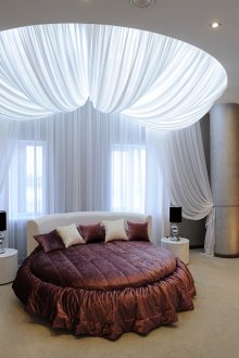 Λευκό στρογγυλό κρεβάτι Βουργουνδίας στο υπνοδωμάτιο με διακόσμηση από ύφασμα