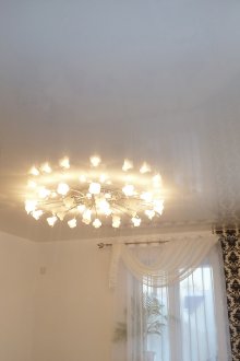 Ένας μικρός πολυέλαιος με μια λευκή τέντα στο σαλόνι