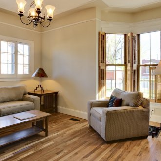 Πολυέλαιοι και επιτραπέζιοι λαμπτήρες σε ένα καθιστικό με δύο παράθυρα