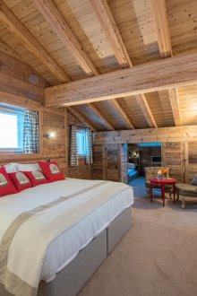 Ευρύχωρο υπνοδωμάτιο με κόκκινα μαξιλάρια εξοχικής κατοικίας κάτω από την οροφή