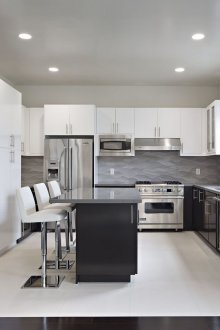 Μαύρη και λευκή κουζίνα με γκρίζους πάγκους.