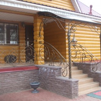 Όμορφο κιγκλίδωμα από σφυρήλατο σίδερο της βεράντας ενός εξοχικού σπιτιού.