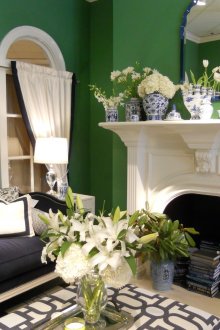 Καθιστικό με πράσινους τοίχους και λευκό στυλιζαρισμένο τζάκι