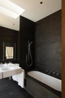 Μαύρη πέτρα πλακάκια σε μια άσπρη μπανιέρα