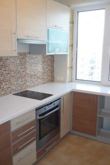 Ψυγείο κάτω από το παράθυρο στη γωνιακή κουζίνα