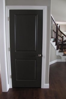 Μαύρη πόρτα και σκούρο καφέ φύλλα στο δωμάτιο