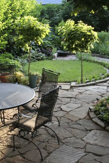 Μεταλλικά έπιπλα, δέντρα και λουλούδια στο σχεδιασμό της αυλής