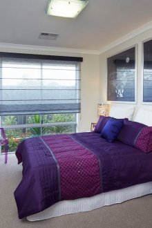 Μωβ κρεβάτι σε μια λευκή κρεβατοκάμαρα