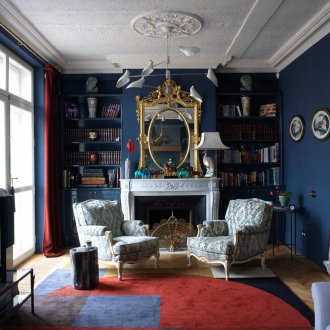 Μπλε τοίχους και κόκκινες κουρτίνες και έμφαση στο χαλί στο σαλόνι