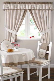 Διακόσμηση παραθύρου με κουρτίνες κρέμας με μια λαμπρέκι στην κουζίνα