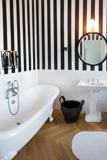 Ο συνδυασμός μιας απλής λευκής επιφάνειας και τα ασπρόμαυρα ριγωτά ταπετσαρία στο μπάνιο