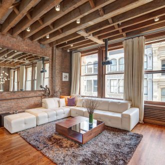 Ξύλινα δοκάρια στην οροφή στο σαλόνι με τοίχους από τούβλα.