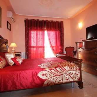 Κόκκινες χρυσές κουρτίνες και κρεβάτι στο υπνοδωμάτιο