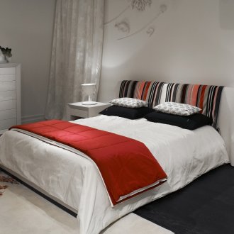 Μια πληθώρα διαφορετικών πηγών φωτός σε μια λευκή κρεβατοκάμαρα με κόκκινες προθέσεις